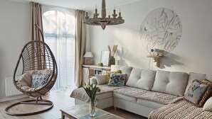 A living room with a curved chair, a sofa, a coffee table, and a chandelier.