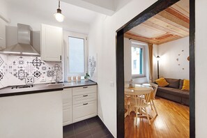 Een moderne keuken met witte kasten, een roestvrijstalen afzuigkap en een betegelde achterwand.