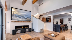A modern living room with a fireplace, leather sofas, a wooden coffee table, and a large TV mounted on the wall. - Moose Mgmt at Upper Main 301 (Park City)