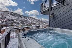 Boblebad på en balkon med udsigt over en sneklædt bjergby.