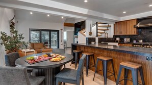 A modern kitchen with a central island, bar stools, and a dining area with a round table. - Moose Mgmt at Upper Main 301 (Park City)