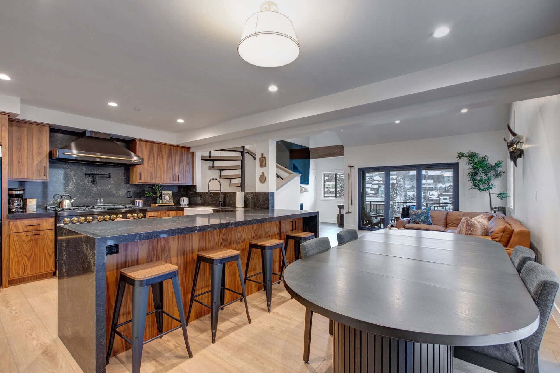 Una cocina moderna con una isla central, taburetes de bar y una gran mesa de comedor.