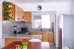 A modern kitchen with granite countertops, wooden cabinets, a built-in stove, and a refrigerator. - 3 BR Villa With Private Pool and Jacuzzi (Punta Cana)