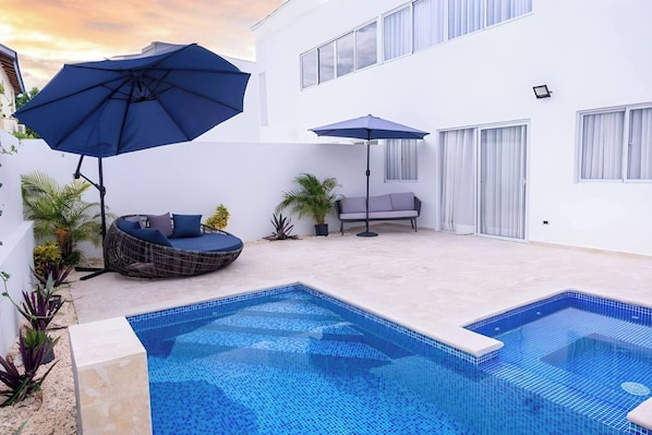 A swimming pool with a sun lounger and a seating area with umbrellas. - 3 BR Villa With Private Pool and Jacuzzi (Punta Cana)