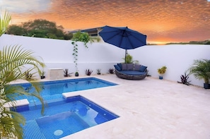 A swimming pool with a blue tiled floor, surrounded by a white wall and a few potted plants. - 3 BR Villa With Private Pool and Jacuzzi (Punta Cana)