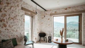 Une chambre moderne avec des murs en pierre, une table ronde, une chaise et une vue sur la ville.