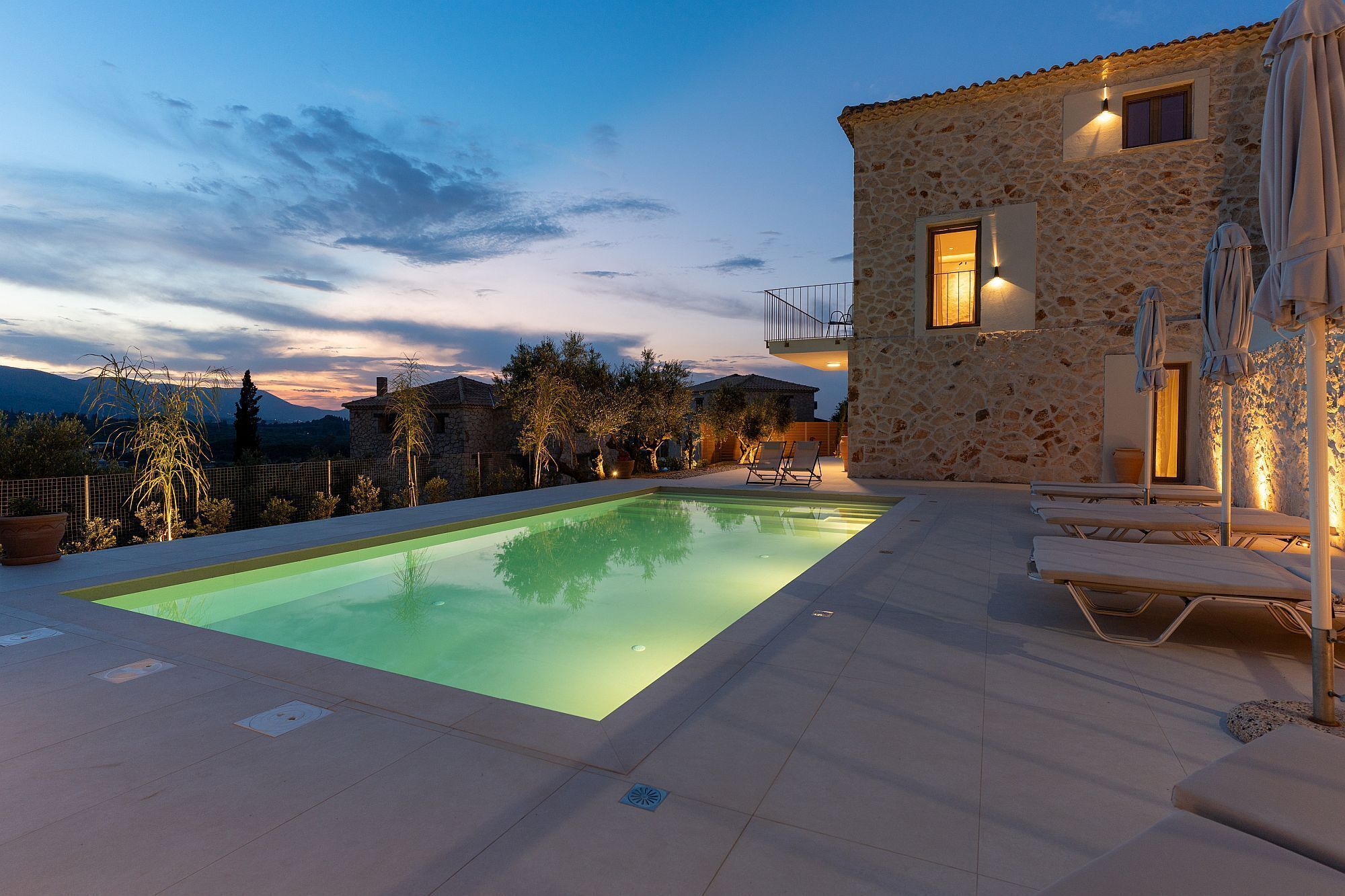 A stone building with a swimming pool and lounge chairs.