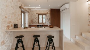 Une cuisine moderne dotée d’un îlot central, de tabourets de bar, d’une fenêtre et d’un escalier.