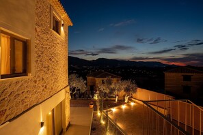 A stone building with a balcony overlooking a landscaped area with trees and a distant mountain range. - Novel Villa - 5 bedrooms & Private Pool (Zakynthos)