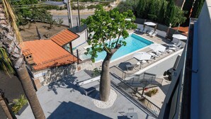 A rooftop pool area with a tree, lounge chairs, and umbrellas. - park hotel la corte & spa (Palma Campania)