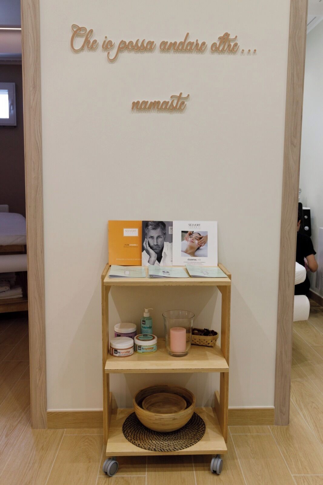 Una estantería de madera con productos para el cuidado de la piel, una foto enmarcada y un letrero con un mensaje.