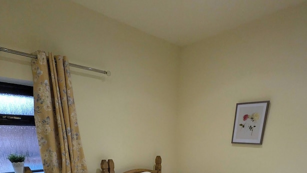 A bedroom with a wooden four-poster bed, a nightstand with a lamp, a window with curtains, and a framed picture on the wall. - The Tack Room With Hot Tub (Doncaster)