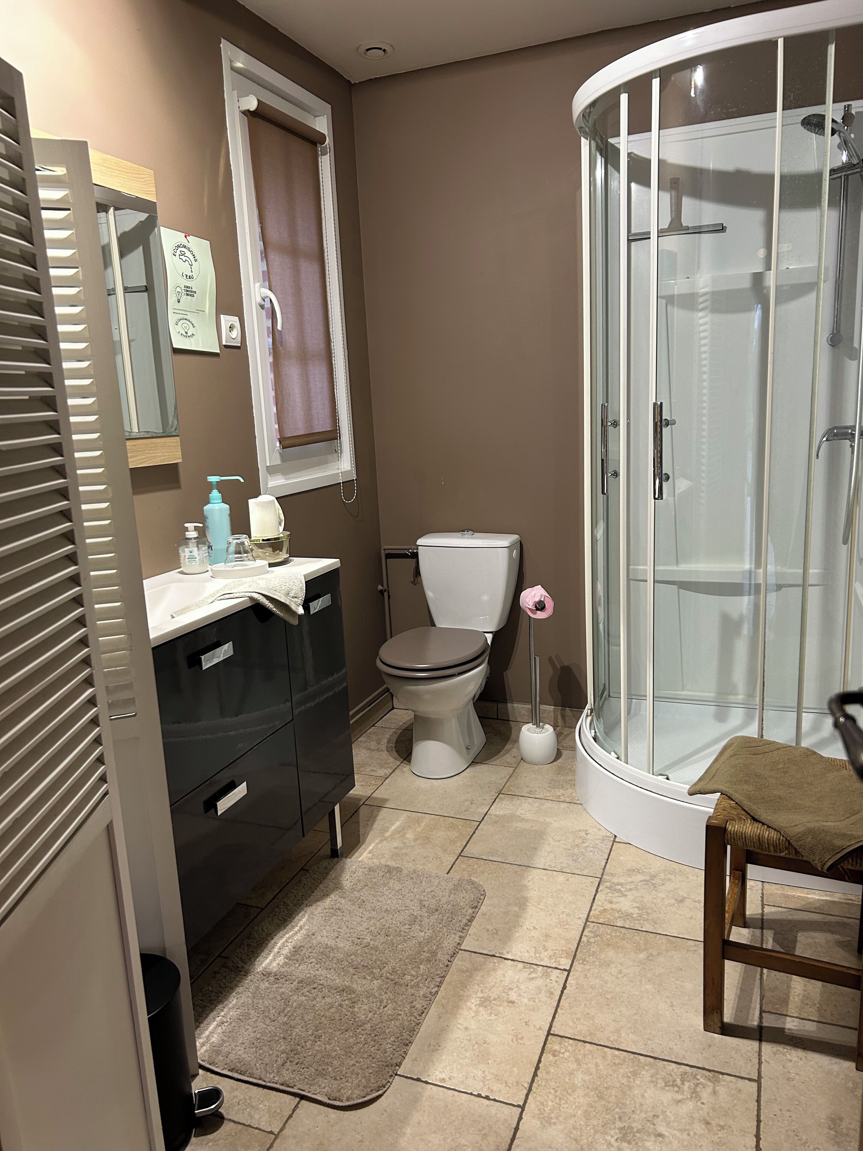 Ein Badezimmer mit Toilette, Waschbecken, Spiegel, Duschkabine und Handtuchhalter.