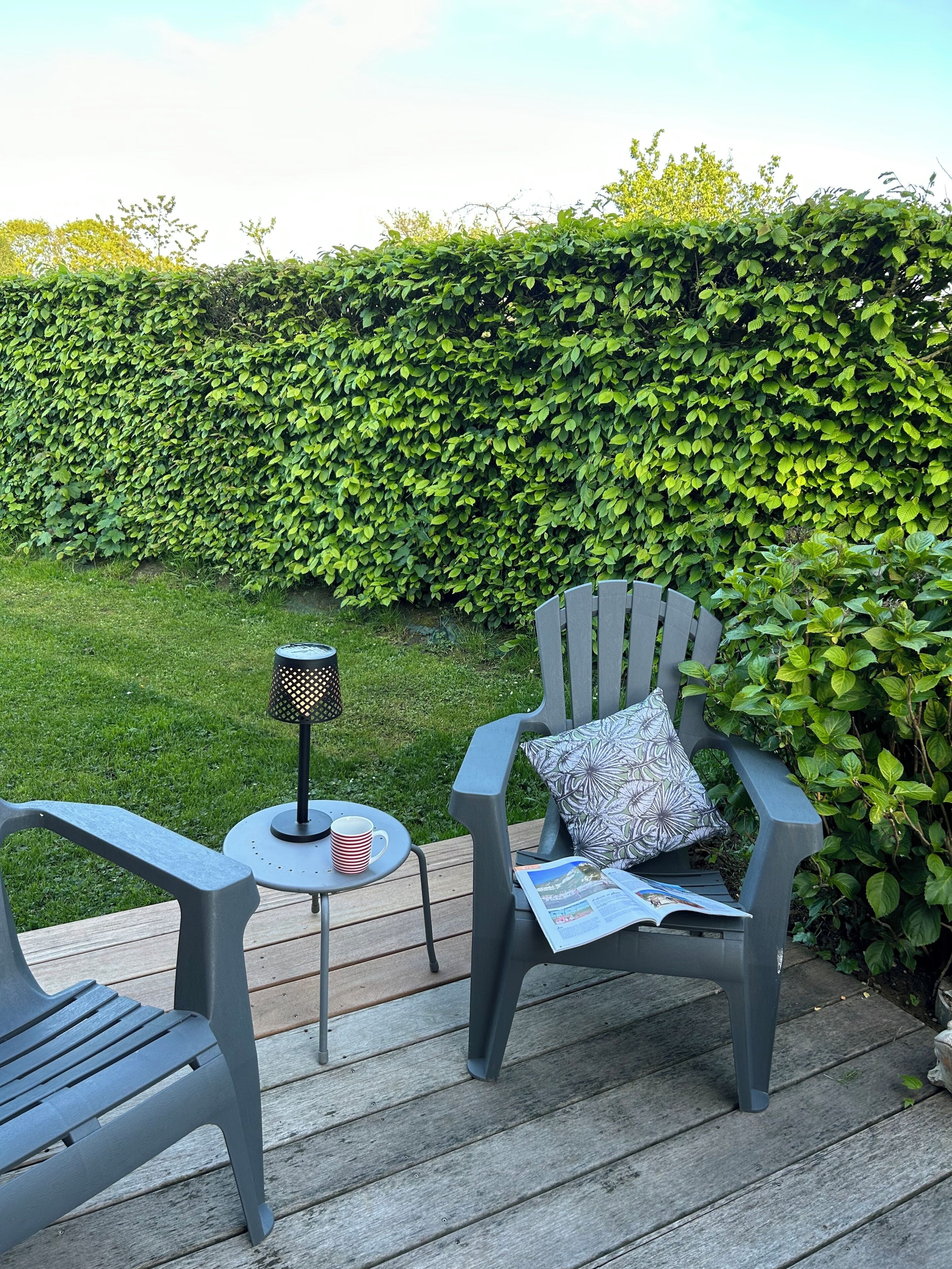 A patio with two chairs, a small table, and a lamp.