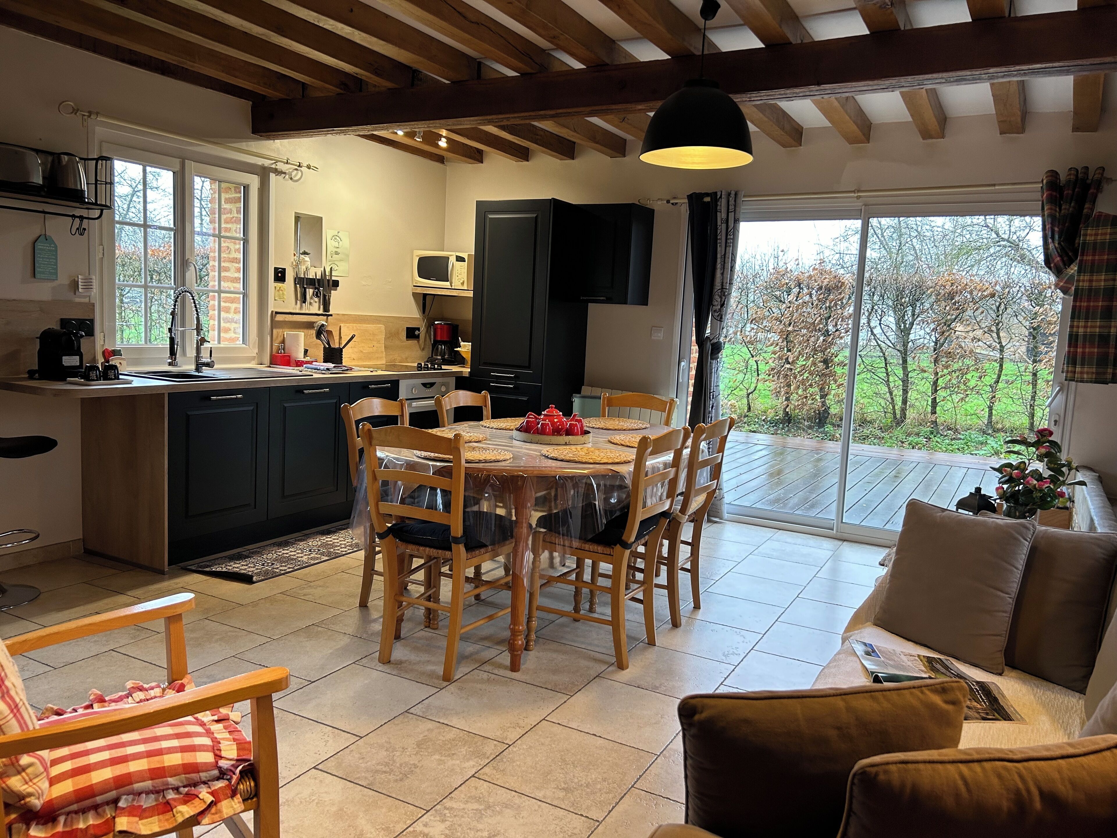 A cozy kitchen with a dining area, wooden beams, and a view of the outdoors.