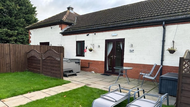 A house with a patio area, a barbecue, and two lounge chairs. - The Stables Cottage With Hot Tub - NO PE (Doncaster)