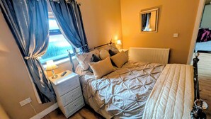 A bedroom with a bed, nightstand, lamp, and a window with curtains. - The Stables Cottage With Hot Tub - NO PE (Doncaster)