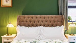 Una cama bien hecha con una colcha estampada, dos lámparas de noche y un cuadro en la pared.