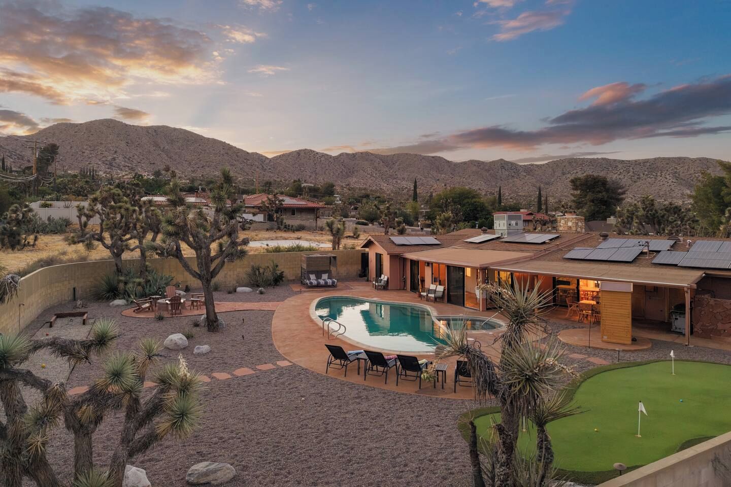 A residential area with a swimming pool, outdoor seating, and solar panels.