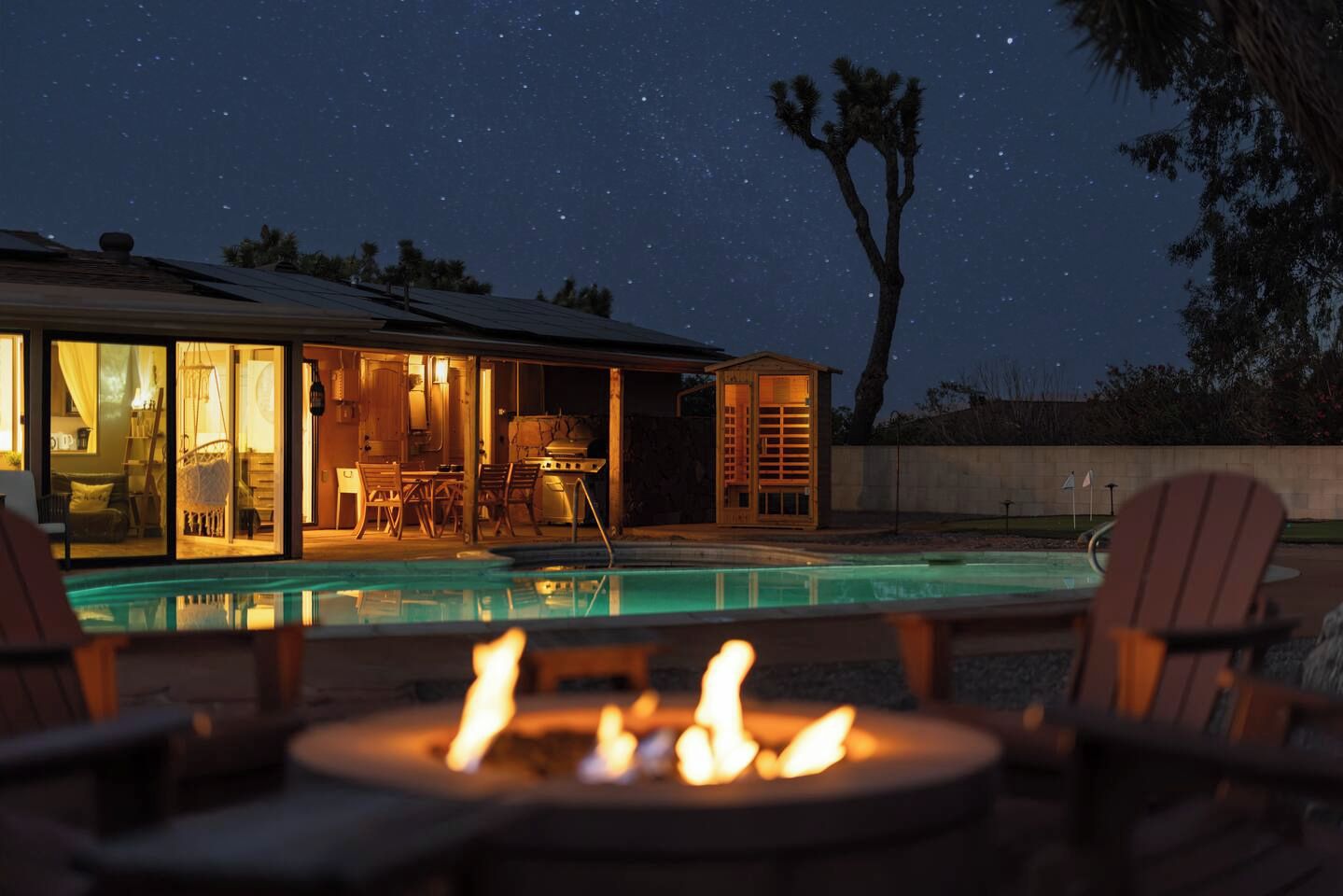 A poolside area with a fire pit, outdoor furniture, and a building with glass doors and windows.