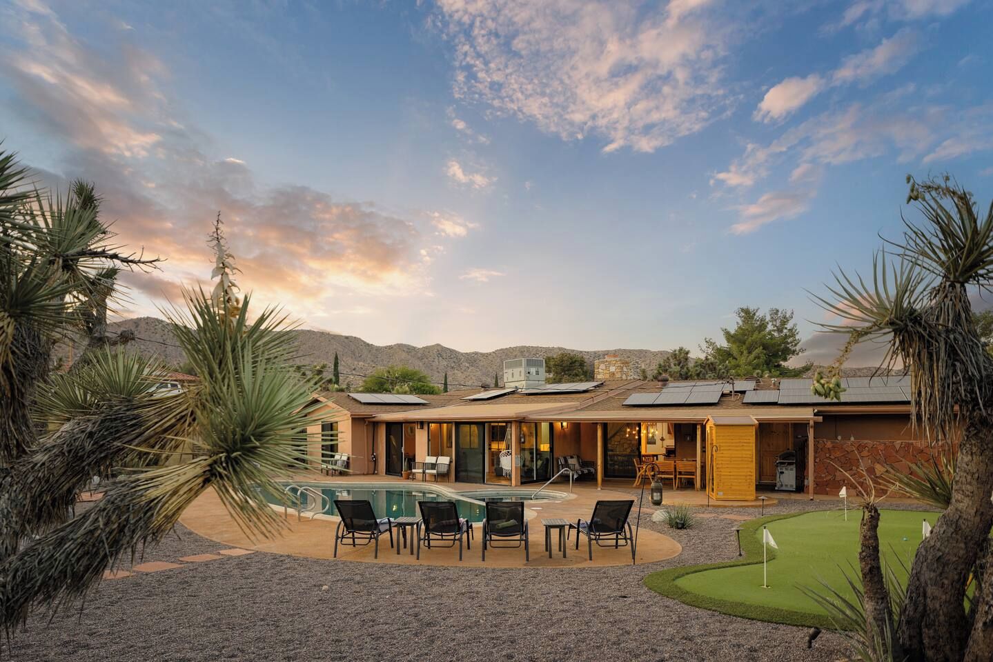 Une maison moderne dotée d’une piscine, d’un espace salon extérieur et d’un terrain de golf.