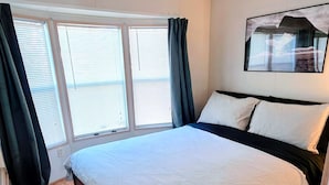 Ein Schlafzimmer mit einem großen Bett, einem Deckenventilator und einem Fenster mit Jalousien.