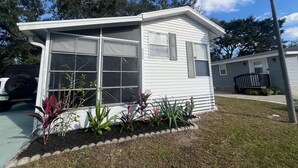 Ein kleines, eingeschossiges Haus mit Garage, ein Veranda und ein gepflegter Garten.