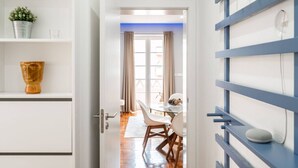 A modern interior with a dining area, a white cabinet with a plant, and a blue shelving unit. - Stylish T2 Apartment in Lisbon by Lisbeyond (Lisbon)