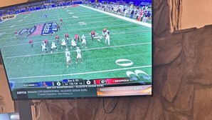 A television mounted on a stone wall displaying a football game, with a fireplace below. - SW-59 Deaver's Delight  Newly remodeled (Beech Mountain)