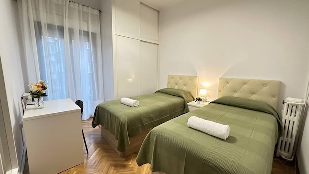 Une chambre d’hôtel avec deux lits, un bureau et un radiateur.