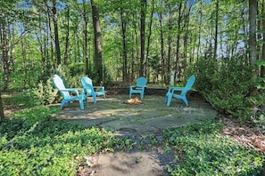 Un espace boisé équipé d’un foyer et de quatre chaises Adirondack.