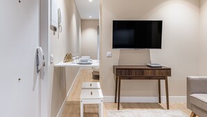 A modern living room with a flat-screen TV mounted on the wall, a wooden coffee table, and a grey sofa. - Waou Essence VI Antón Martín - Short Duration (Madrid)