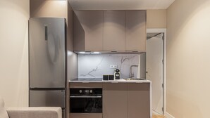 A compact kitchen with a built-in oven, a stainless steel refrigerator, and a marble backsplash. - Waou Essence VI Antón Martín - Short Duration (Madrid)