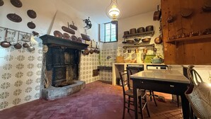 A traditional kitchen with a stone fireplace, wooden cabinets, and a hanging light fixture.