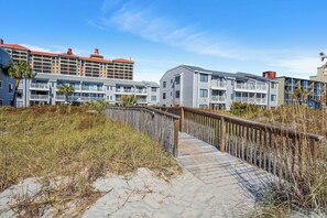 Un hôtel situé en bord de mer, avec une promenade en bois menant aux bâtiments.