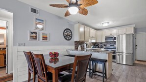 A modern kitchen with wooden cabinets, a central island, and a stainless steel refrigerator. - Sea Cloisters II Ocean Front Beach Retreat (North Myrtle Beac)