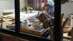 A kitchen with a dining table set for two, a refrigerator, and a hanging pot rack. - Charming gîte nestled in the heart of the Opal valleys, near Montreuil/mer (Marenla)