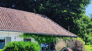 A house with a tiled roof, a porch, and a garden with various plants and flowers. - Charming gîte nestled in the heart of the Opal valleys, near Montreuil/mer (Marenla)