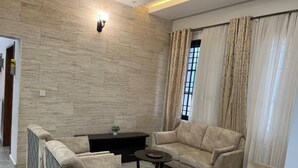 A living room with a sofa set, a coffee table, and a TV stand. - Luxery 3-bedroom villa with ACs in a secure and assessable neighborhood in Limbe (Limbe)