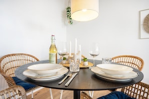 Une table de salle à manger ronde, avec de l’assiette blanche, des couverts et une bouteille de vin.
