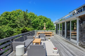 Eine Terrasse mit Gartenmöbeln, einem Holztisch und einem Blumentopf.