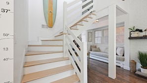 Un escalier avec une rampe blanche, des marches en bois et une indication de la hauteur sur le mur.