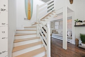 Un escalier avec une rampe blanche, des marches en bois et une indication de la hauteur sur le mur.