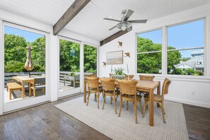 A dining area with a table and chairs, large windows, and a ceiling fan. - Luxury Coastal Retreat in the Private Gated Community (2426) (West Yarmouth)