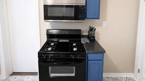 Une cuisine de taille réduite avec un four noir, un four à micro-ondes et des placards bleus.