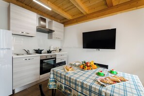 Eine moderne Küche mit weißen Schränken, einer Edelstahl-Dunstabzugshaube und einem flachbildfernseher an der Wand.