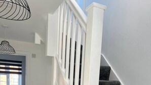 A staircase with white railings and dark carpeted steps leading to a second floor. - Gatwick 3 Bed Parking (Surrey)