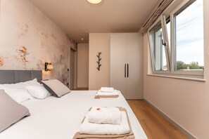 Ein modernes Schlafzimmer mit einem großen Bett, einem Kleiderschrank und einem Fenster mit Blick.