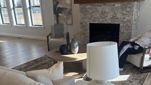 Ein modernes Wohnzimmer mit Kamin, einer Couch, einem Couchtisch und einer Lampe.