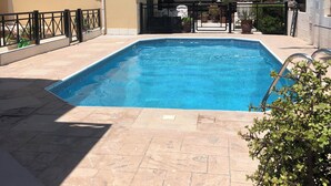A swimming pool with a tiled deck, surrounded by a building with a balcony and a fence. - Sunset View, perfect holiday home located on the edge of Polis (Polis)